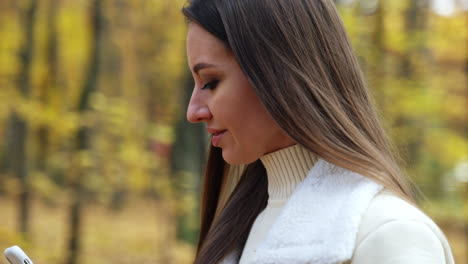 mujer usando el teléfono en un parque de otoño
