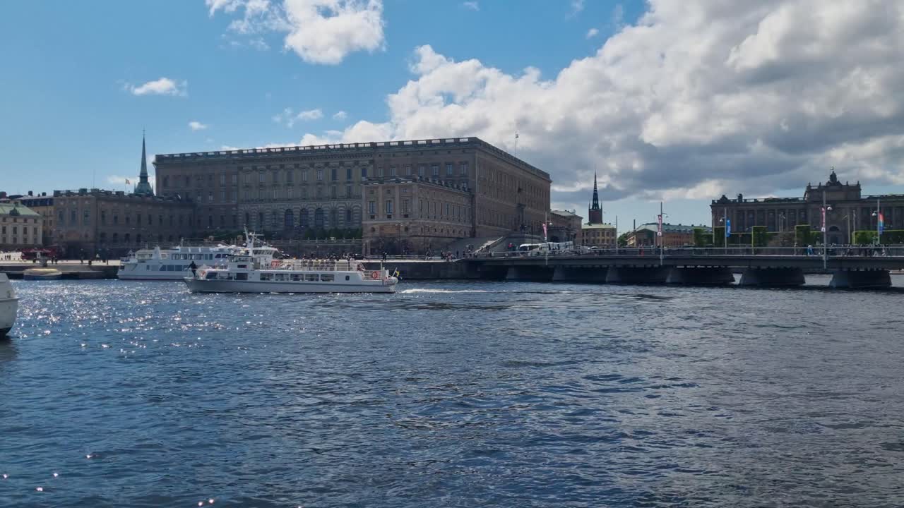 Udsigt over Stockholms ström mod Stockholms kongelige palads i Sverige med en passagerfærge, der glider forbi foran det historiske vartegn under en klar, solrig himmel.
