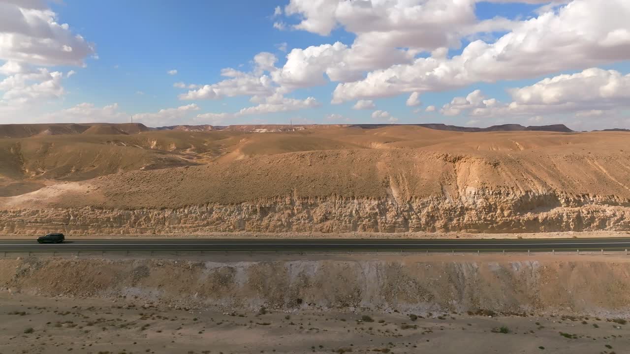 coche zoomando hacia el norte en una carretera del desierto con cielo azul nublado