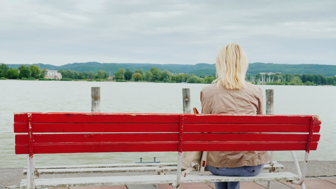 빨간 벤치에 여자는 호수를 존경