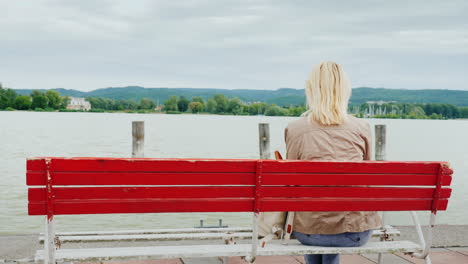 Woman-on-Red-Bench-Admires-a-Lake