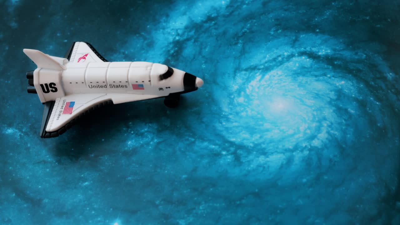Close up of a miniature toy space shuttle placed on a blue cosmic galaxy backdrop
