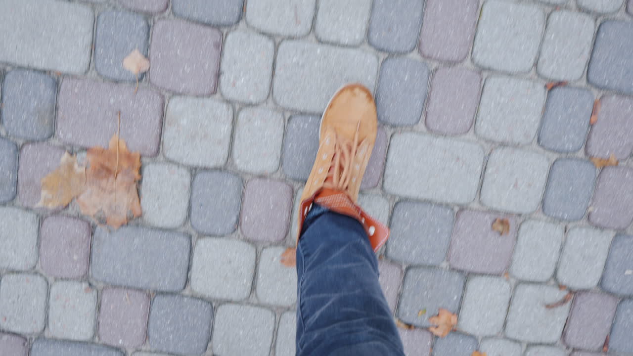 Feet In Boots Walking On The Sidewalk Paved With Tiles