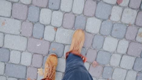 Feet-In-Boots-Walking-On-The-Sidewalk-Paved-With-Tiles