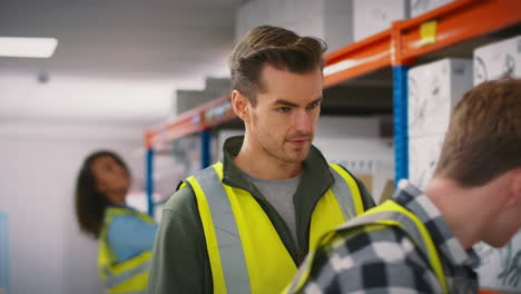 male team leader with digital tablet in warehouse training intern standing by shelves