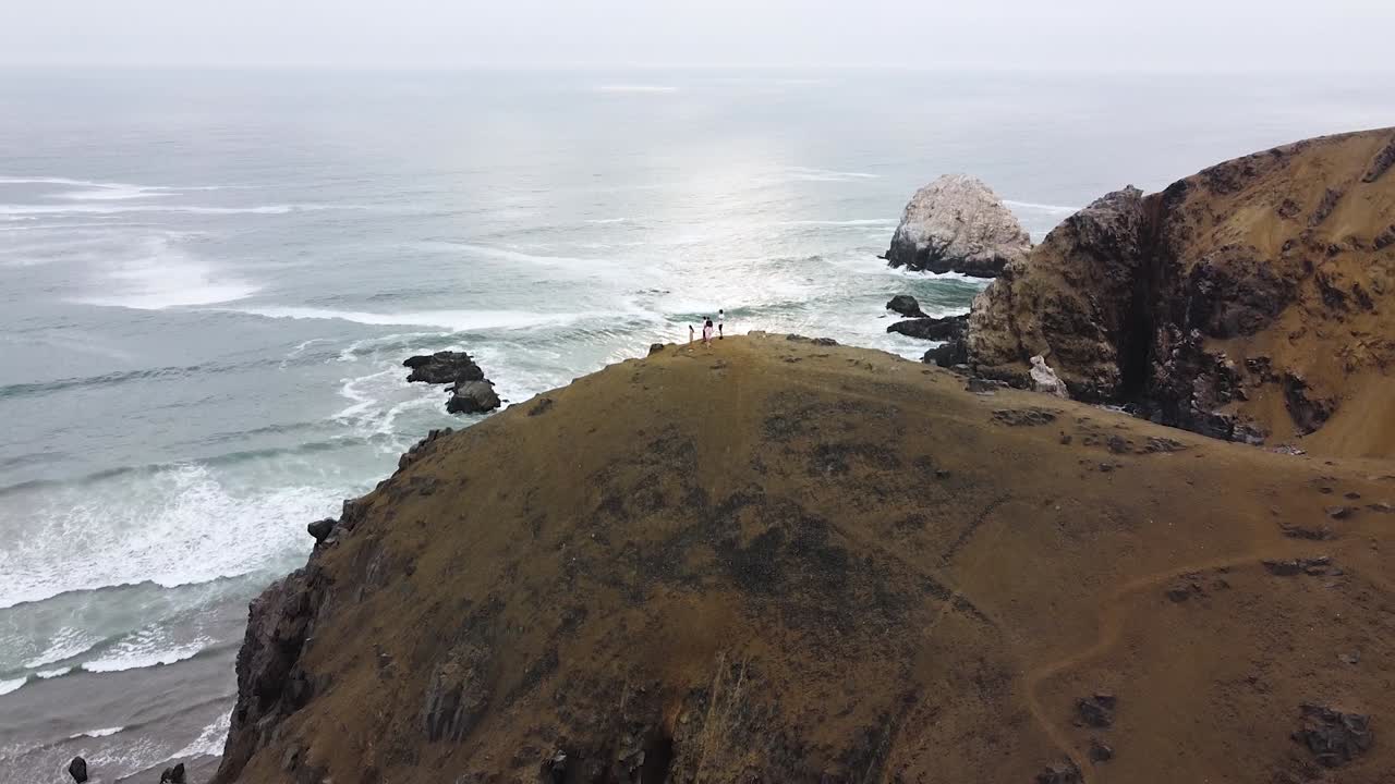 grupo de excursionistas en la cima de una montaña junto a una playa durante la puesta de sol en la costa de perú