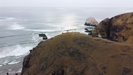 一群徒步旅行者在秘鲁海岸的海<unk>旁边的山顶上日落