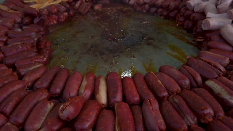 spanish chorizo sausages stacked in circle around large frying pan, closeup