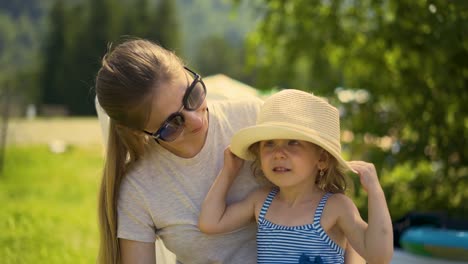 Close-up-Travelling-Mom-and-daughter-are-sitting-on-the-beach-near-the-bushes