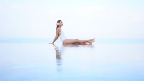 heavenly scenery, slender exotic woman by infinity swimming pool, tropical sea in skyline, full frame