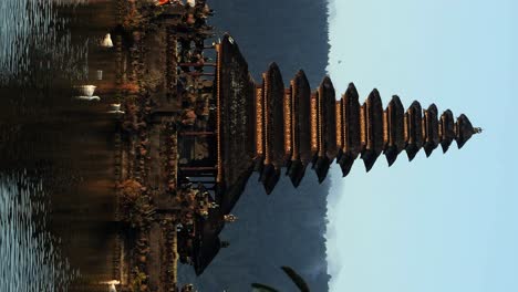 disparo de inauguración vertical de pura segara ulun danu un templo espiritual en el agua en bali con agua reflejada y vista de patos, naturaleza y la hora dorada
