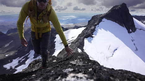 low, top down view of mountaineer climbing towards camera on ridge in norway