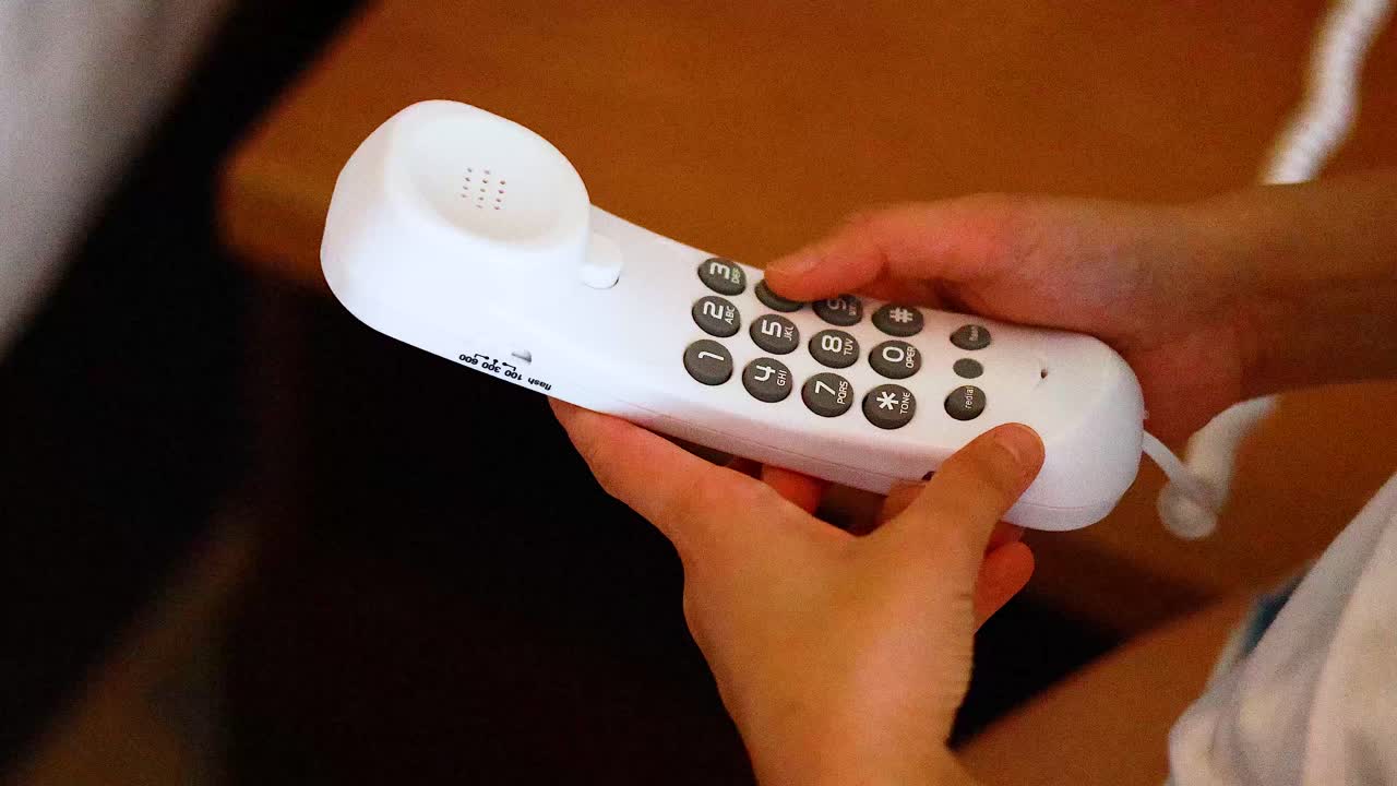 persona interactúa con un teléfono de hotel