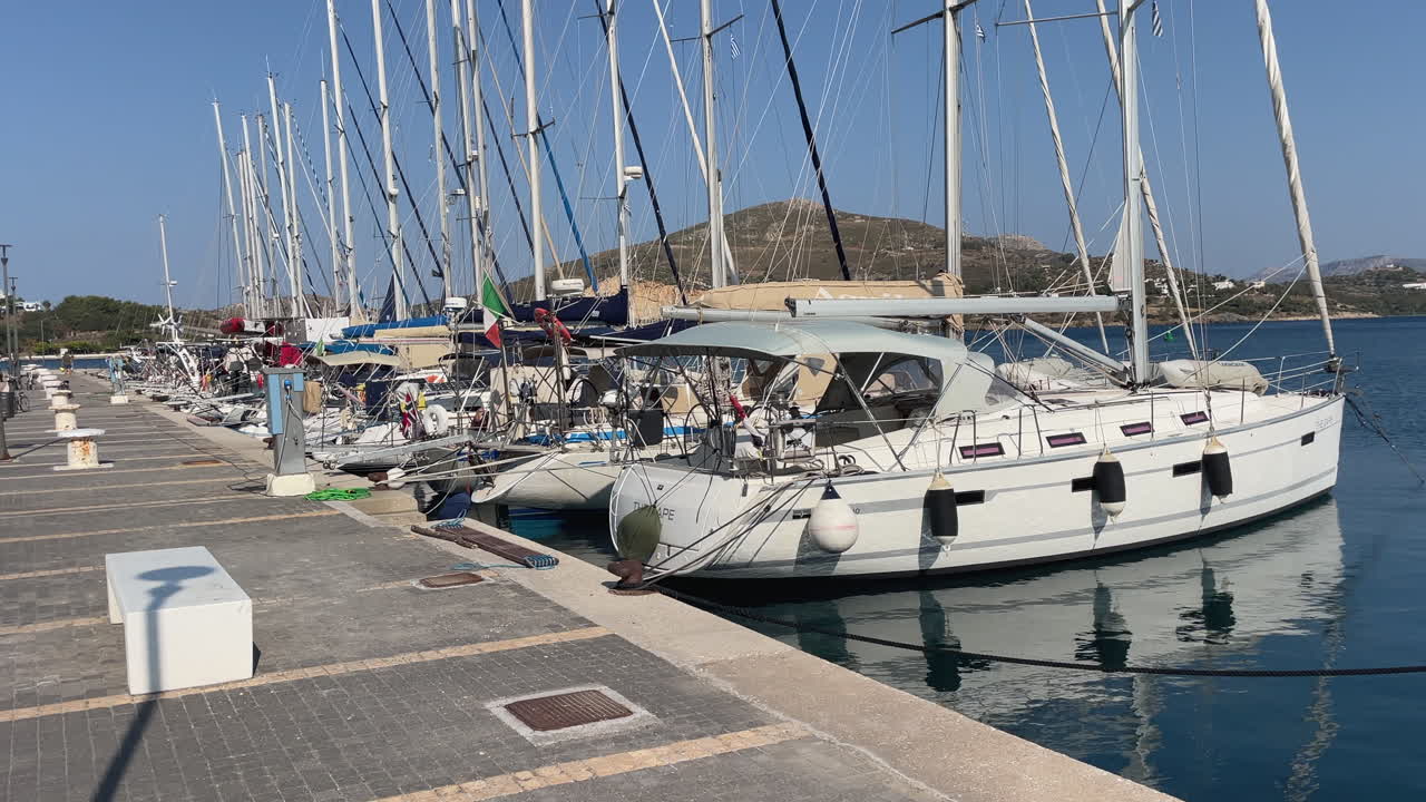 Greece, Leros Island, Lakki Marina on a sunny day with blue skies. Sailboats flush-seamed on the calm water, flags of the boats side by side, nobody at the marina, early in the morning.