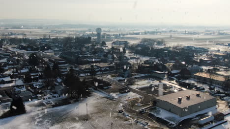 aerial snow falls over american township on grey winter day