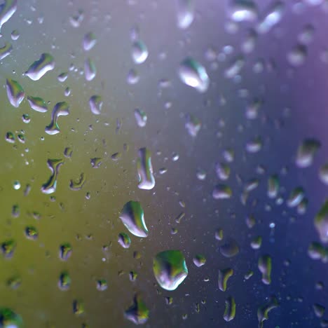 water drops following down on window glass. drops of rain trickling down isolated. droplets running down. colored background