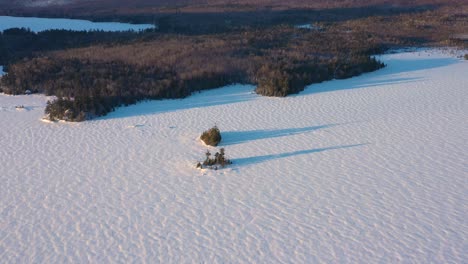 aerial orbit around two islands in a frozen lake with a tilt up to reveal the mountain behind