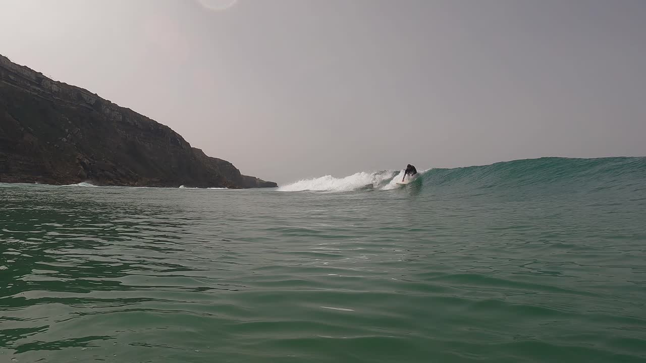 View of some strong rider generating some speed on a perfect waves in Praia da Aguda, Sintra, Portugal