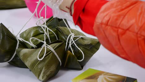 bunch of asian rice triangles wrapped in leaf tied together with string and placed on table filmed as close up