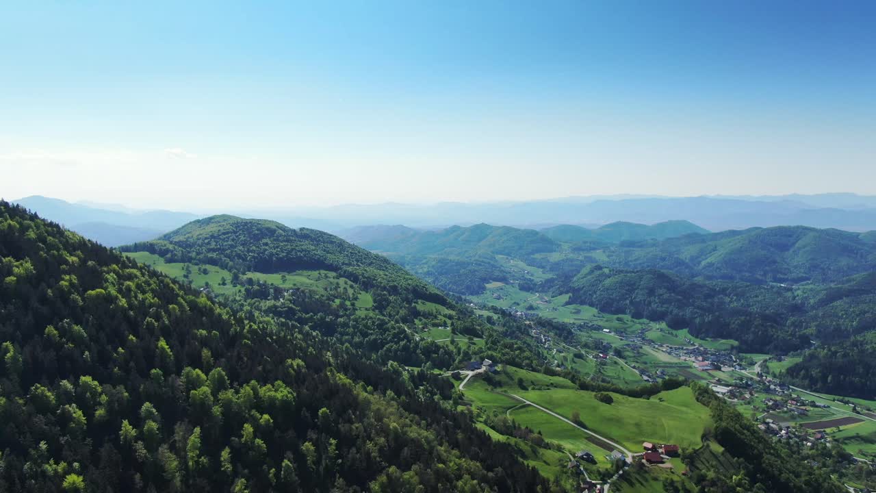 Aerial Pan Right Over Lush Green Forests With Mountain Landscape In The Background