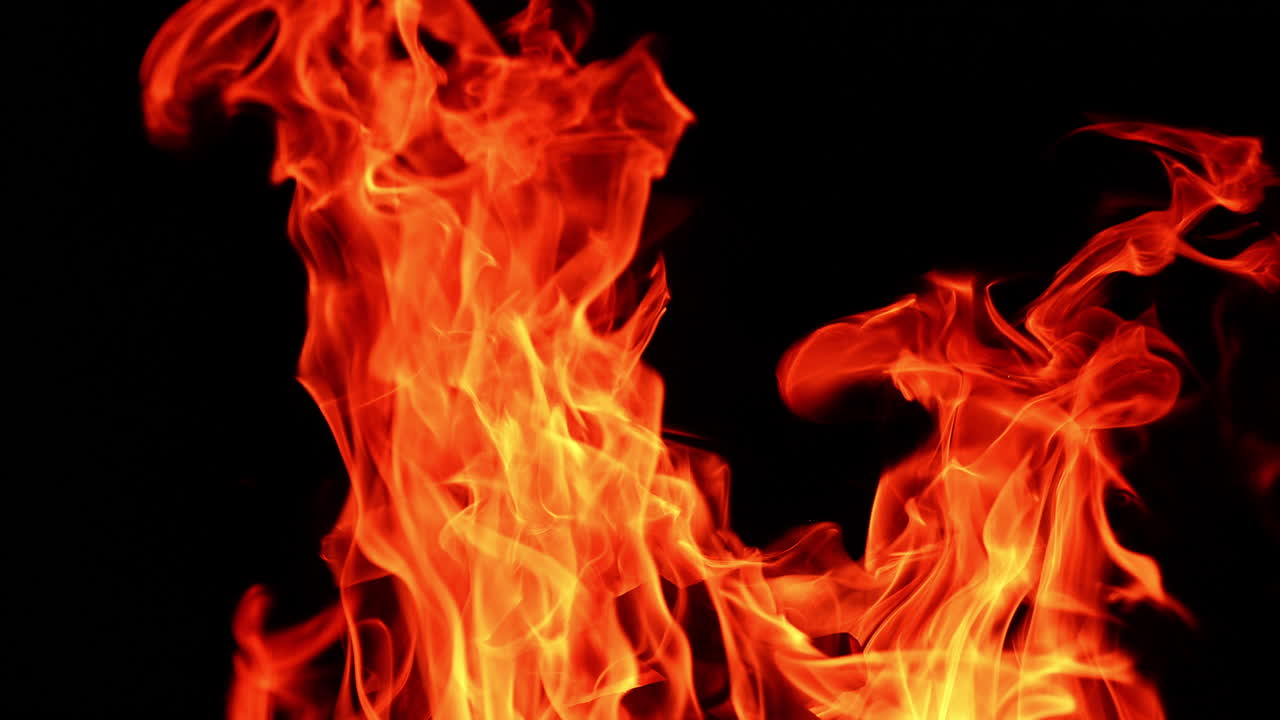 Fire flames licking the darkness. Hot dangerous campfire burning isolated at night. Close up.