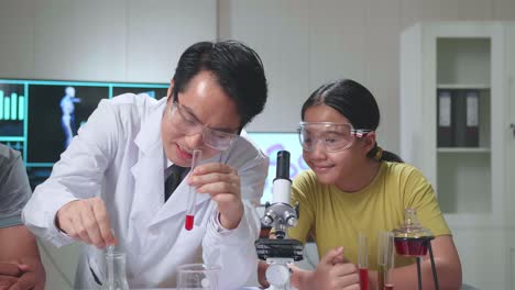 young asian boy and girl exciting while learning science experiment in laboratory with teacher in classroom. study with scientific equipment and tubes