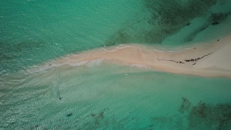 a narrow sandy strip in clear turquoise waters, aerial view