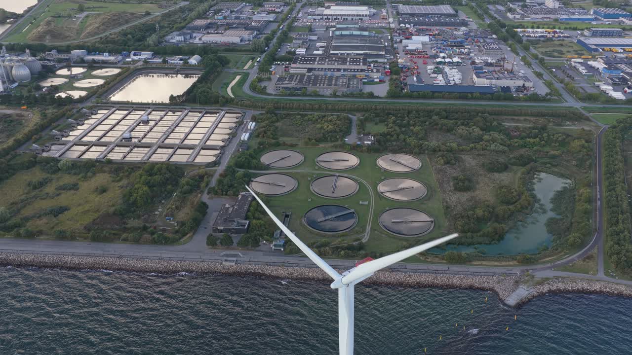 Modern water treatment works beside a wind turbine in a city setting