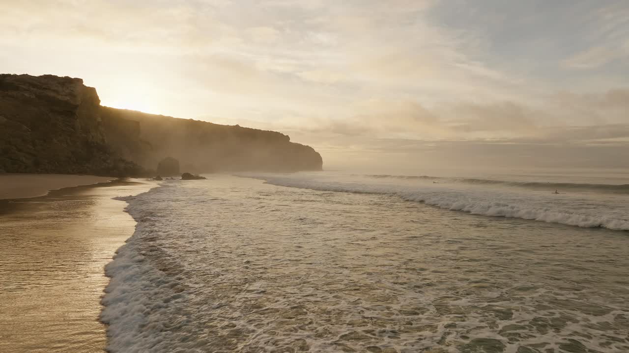 volando sobre la playa de arena dorada acercándose a formaciones de roca caliza, algarve, portugal