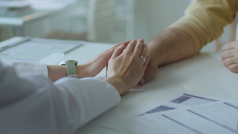 Hands of Caring Female Doctor Supporting Patient at Clinic