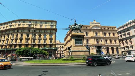 cars pass by a central naples statue