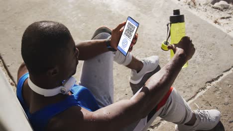 man in street holding smartphone with covid vaccination certificate and qr code on screen