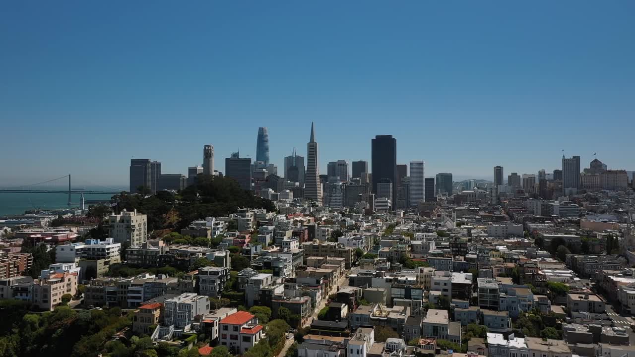 Vibrant aerial footage capturing San Francisco's urban sprawl with skyscrapers, clear blue sky, and distant hills, showcasing a sunny cityscape from above