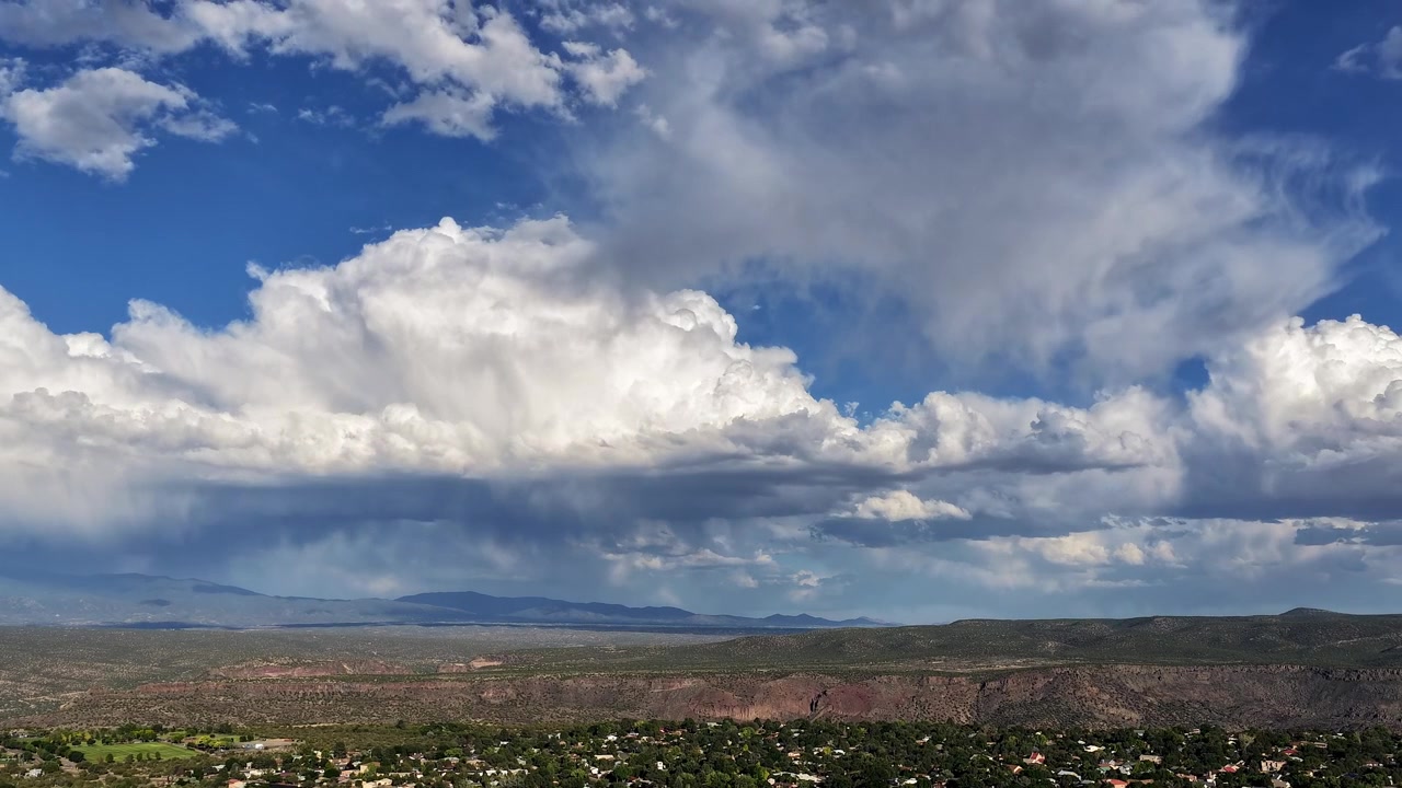 4K UHD drone-timelapse, der viser dynamisk ørkenklima. En massiv monsunstormsky bevæger sig hen over en klar blå himmel og kaster store skygger over en forstad og dyb kløftkant