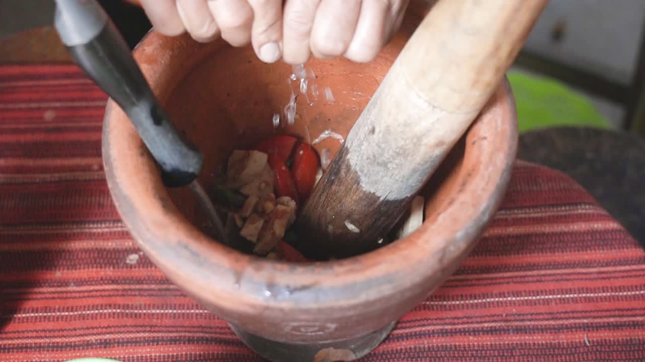 cocinando la serie som tam: la mano del vendedor de comida callejera en cámara lenta exprimiendo jugo de lima en el mortero para hacer som tam o ensalada de papaya verde picante tailandesa, uno de los platos más populares de tailandia