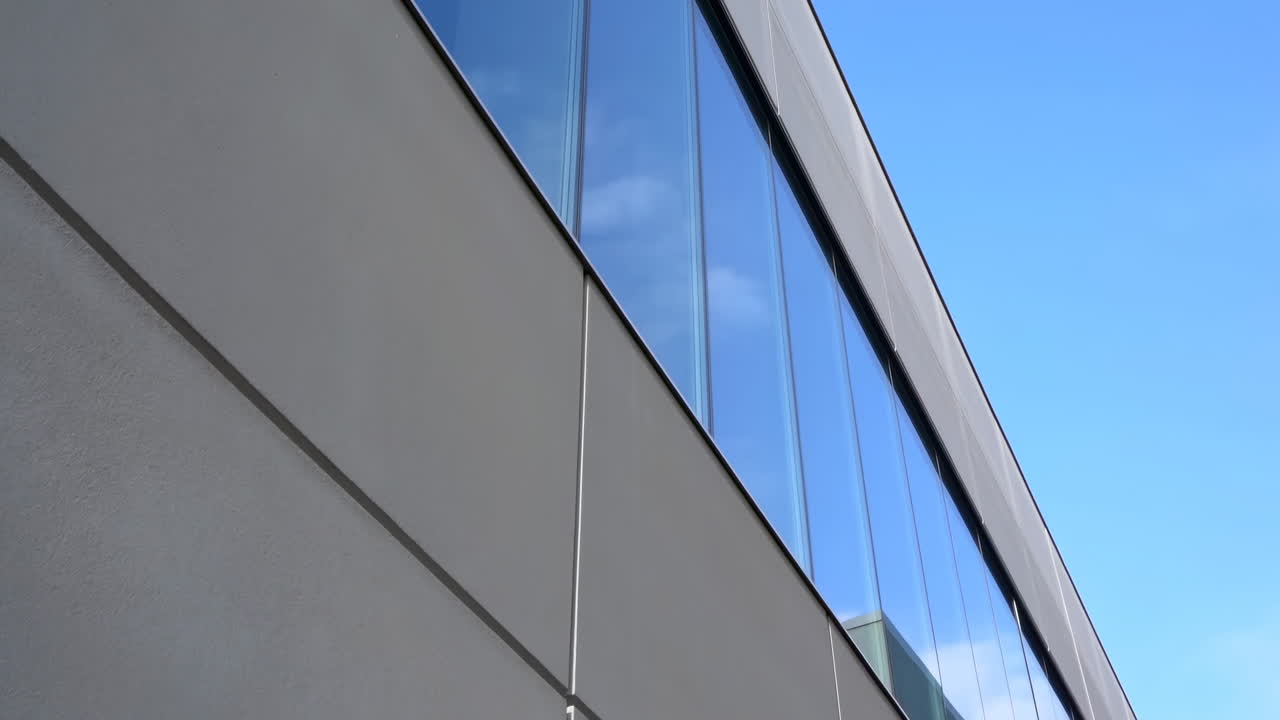 Panoramica verticale lungo la facciata di un edificio moderno con finestre riflettenti