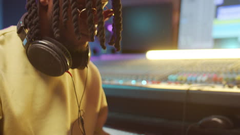 black musician playing synthesizer in recording studio