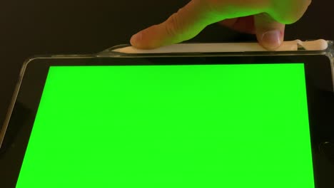 man puts away pen after use on ipad with green screen top view