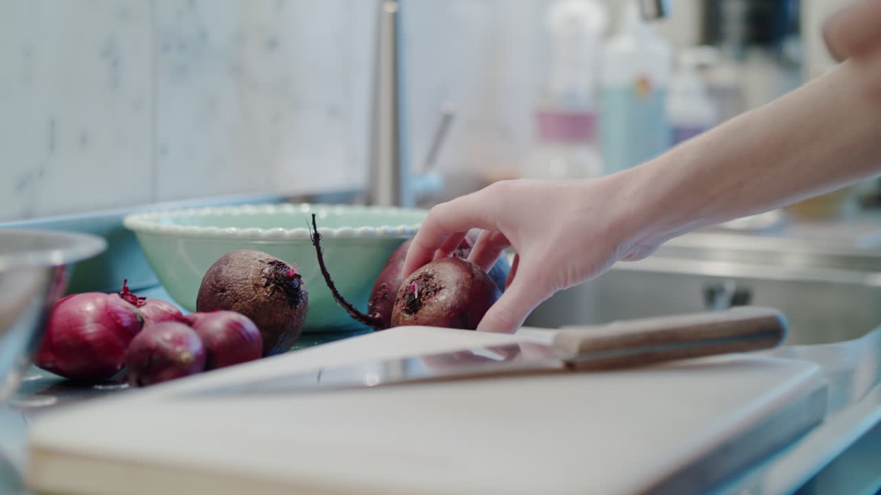A skilled female chef slices a vibrant beetroot on a clean cutting board in her kitchen.