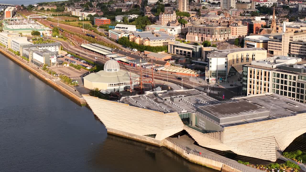 Drone camera smoothly pans over Dundee’s waterfront, highlighting modern architecture, river, and city buildings