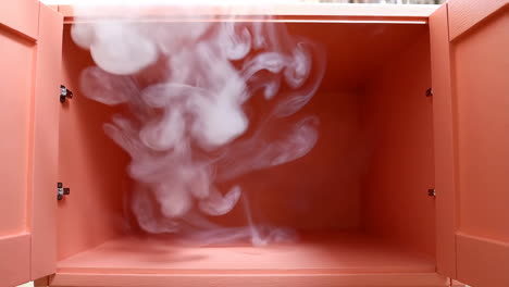 white smoke swirling inside an open pink cabinet