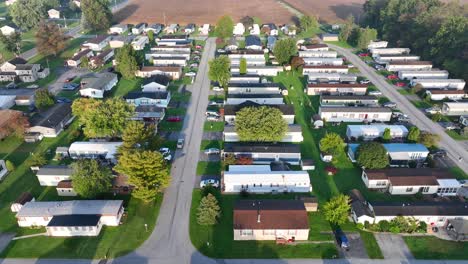 Residential-street-with-rows-of-houses-and-mobile-homes,-green-lawns,-and-trees