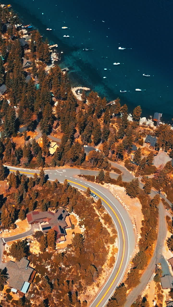 Sunlit wooded waterfront with private cottages among the trees. Amazingly deep blue waters of lake with numerous boats near the shore. Top view. Vertical video