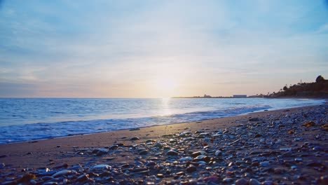 Ocean-waves-at-a-rocky-sand-beach-during-sunset