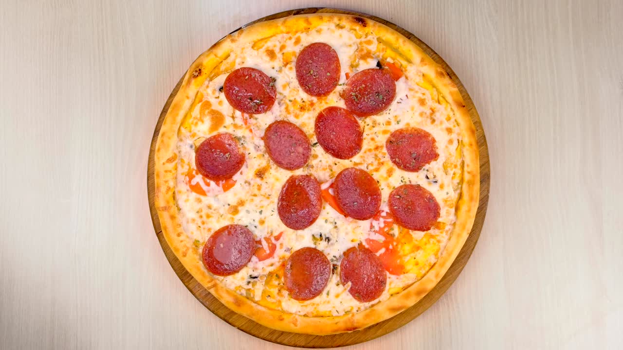 Salami pizza on wooden board on the table.