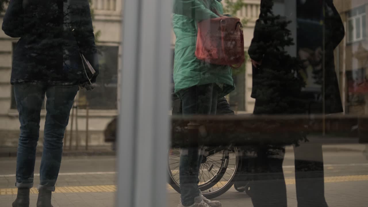 신체적 장애가 있는 사람이 접근 가능한 램프가 있는 도시 교통수단을 기다리고 있습니다.