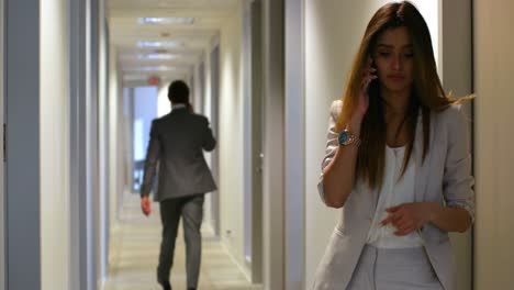 mujer de negocios hablando por teléfono móvil en el corredor 4k