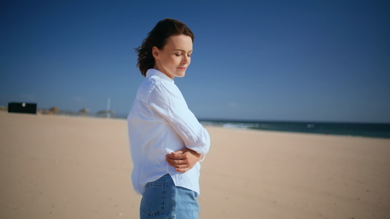 Carefree brunette walking beach adjusting wind blown hair closeup. Happy woman