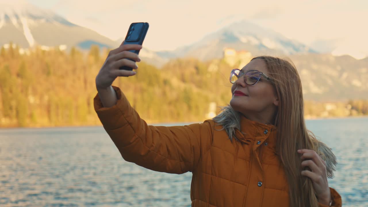 video en 4k de una hermosa joven caucásica tomando una foto selfie en un destino turístico muy famoso, bled, eslovenia.