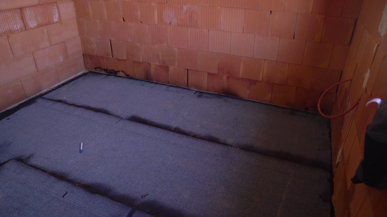 Bitumen membrane covers floor of unfinished house interior for waterproofing